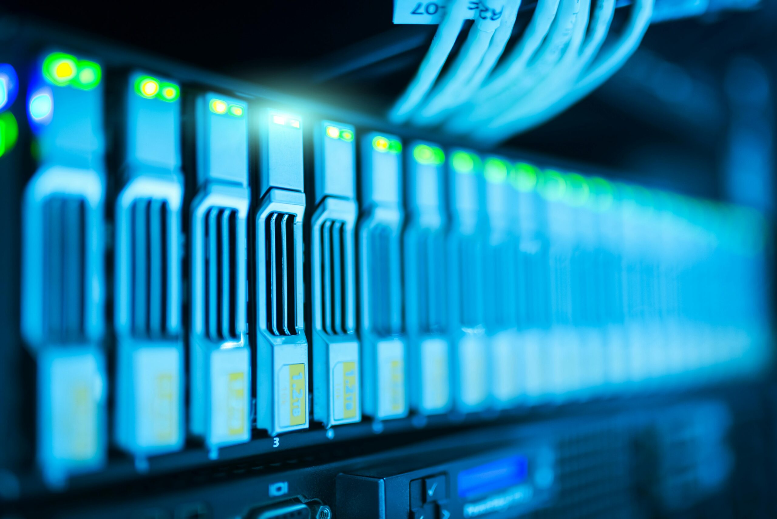 Close-up of a row of active server racks with glowing LED lights and connected cables in a data center. Illuminated by blue light, the scene highlights the technology components, while emphasizing IT Consulting in Contra Costa County to ensure seamless operations.